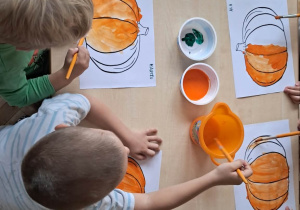 Dzieci malują farbą kontury dyni