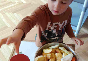 Chłopiec wkłada marchewkę do otworu sokowirówki