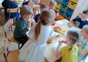 Dzieci spożywają owoce przy wspólnym stole