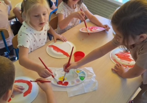 Dzieci malują pędzelkiem talerzyk papierowy