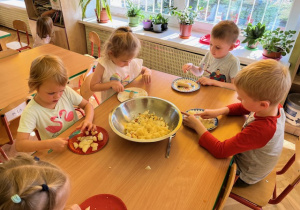 Dzieci skupione na krojeniu sałatki