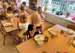 Dzieci z wielkim apetytem jedzą sałatkę jarzynową