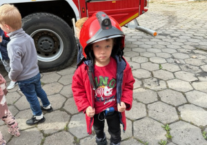 Chłopiec ma kask strażacki