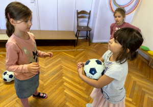 Dziewczynka stoi z piłką naprzeciw koleżance
