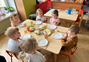 Dzieci słuchają nauczycielki jak mają zrobić sobie kanapkę