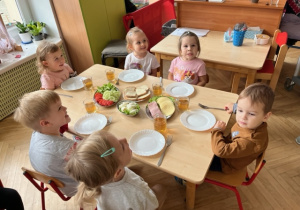 Dzieci siedzą przy stoliku pięknie przygotowanym ze zdrowymi warzywami