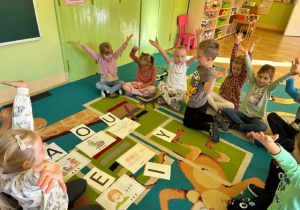 Dzieci pokazują jak wygląda litera "Y" - ręce rozchylone na bok do góry