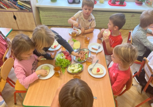 Dzieci z radością jedzą zdrowe kanapki, które same sobie zrobiły