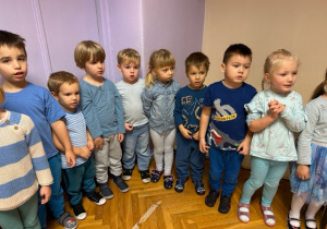 Dzieci ubrane na niebiesko stoją i śpiewają piosenkę