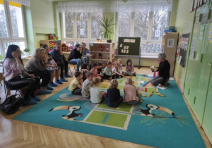 Nauczycielka czyta dzieciom opowiadanie o kurce a dzieci słuchają