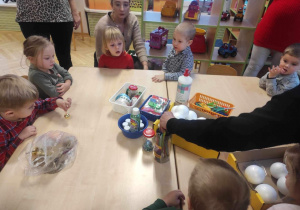 Dzieci i Rodzice siedzą przy stolikach, będą robić dekorację na choinkę