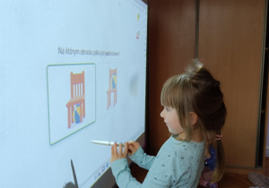 Dziewczynka wykonuje zadanie przy pomocy tablicy multimedialnej