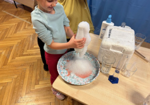 Dziewczynka bawi się pianą z butelki z suchym lodem i żelem do mycia