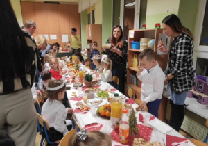 Dzieci wspólnie z Rodzicami siedzą przy wigilijnym stole i kosztują potraw