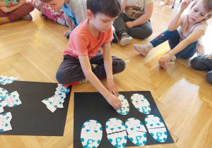 Chłopiec składa obrazki przedstawiające jaja dinozaurów