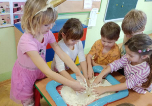 Dzieci wykonują "sztuczny śnieg" za pomocą mąki ziemniaczanej i oleju