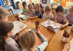 Dzieci oglądają książeczki edukacyjne o Dinozaurach