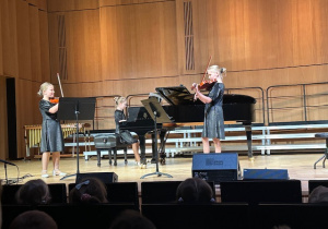 Trio muzyczne- Dwie dziewczynki grają na skrzypcach a dziewczynka trzecia gra na Fortepianie
