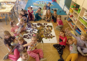 Dzieci pozują do zdjęcia przy wykonanym przez siebie drzewie sensorycznym