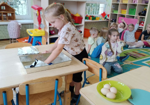 Dziewczynka smaruje blachę do ciasta masłem