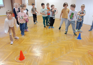 Dzieci celują obręczą w pachołek a następnie losują swoją wróżbę