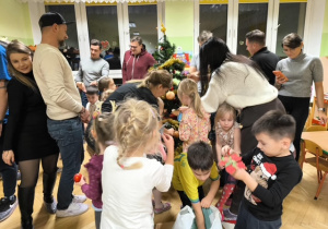 Rodzice i dzieci dekorują choinkę ozdobami