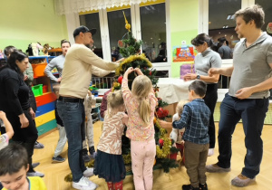 Rodzice i dzieci dekorują choinkę ozdobami