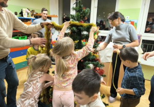 Rodzice i dzieci dekorują choinkę ozdobami