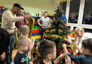 Rodzice i dzieci dekorują choinkę ozdobami