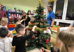 Rodzice i dzieci dekorują choinkę ozdobami