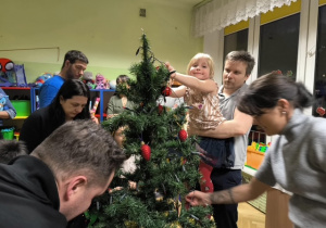 Dziewczynka zawiesza na choince lampki