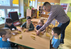 Dzieci siedzą przy stoliku i robią świece z wosku