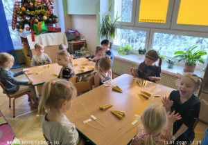 Dzieci siedzą przy stoliku i robią świece z wosku