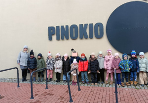 Zdjęcie grupowe na tle logo Teatru Pinokio