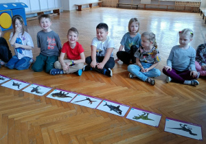 Dzieci oglądają ilustracje dinozaurów i poznają ich nazwy