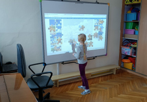 Dziewczynka układa obrazek składający się z interaktywnych puzzli
