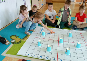 Dziewczynka ustala kierunek poruszania się dinozaura zgodnie z poleceniem