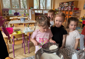 Dziewczynka przesiewa przez sito mąkę