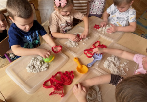 Dzieci bawią się piaskiem kinetycznym formując bułeczki