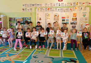 zdjęcie grupowe- dziewczynki pokazują otrzymane od chłopców laurki