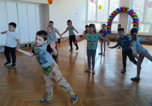 Dzieci wykonują figurę pokazywane na tablicy multimedialnej