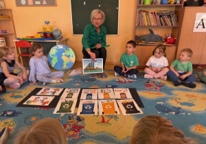 Dzieci siedzą na dywanie i oglądają obrazki o naszej planecie