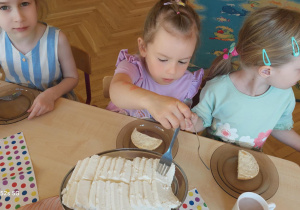 Dziewczynka nakłada na swoją kanapkę ser biały