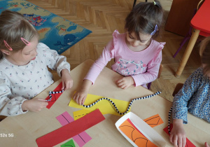 Dzieci układają na śladach linii kolorową wełnę
