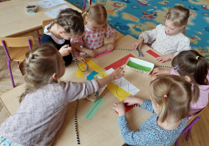 Dzieci z duża dokładnością układają na liniach sznurek