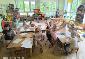 Dzieci siedzą przy stoliku i wykonują pracę plastyczną