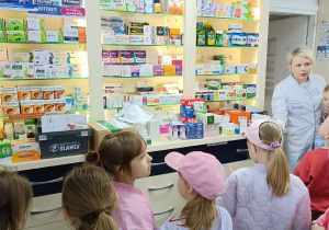 Pani farmaceutka oprowadza dzieci po pomieszczeniach apteki