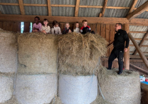 Dzieci siedzą na kopach słomy