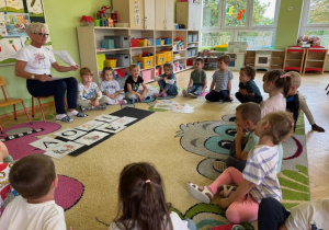 Dzieci siedzą na dywanie i nazywają poszczególne samogłoski"A,O,U,I,E,Y"