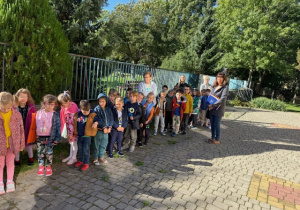 Dzieci i pracownicy stoją na placu przedszkolnym